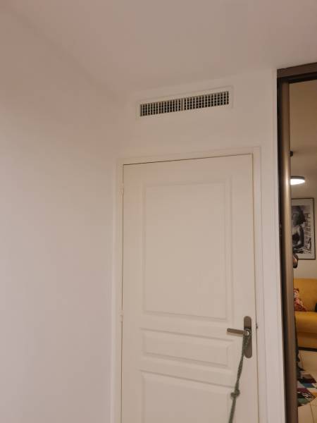 Bouche de soufflage de climatisation intégrée au-dessus d'une porte dans un appartement à Six-Fours